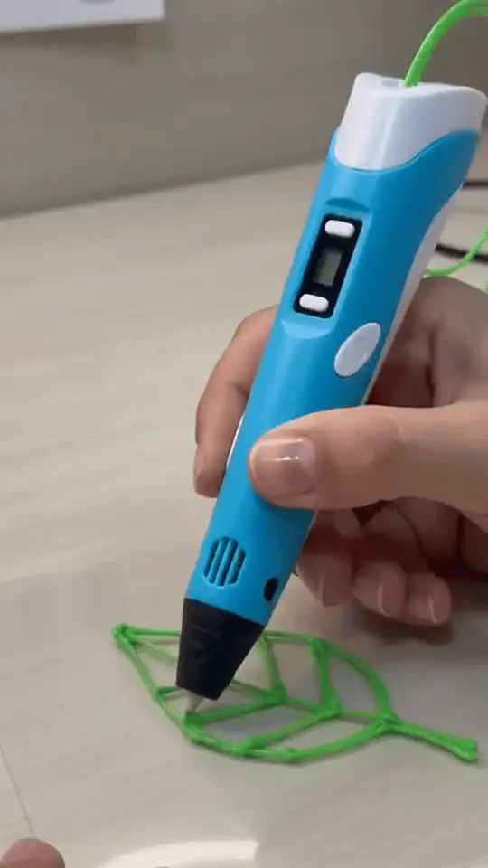 Mão desenhando uma folha e uma casinha com a caneta 3D azul