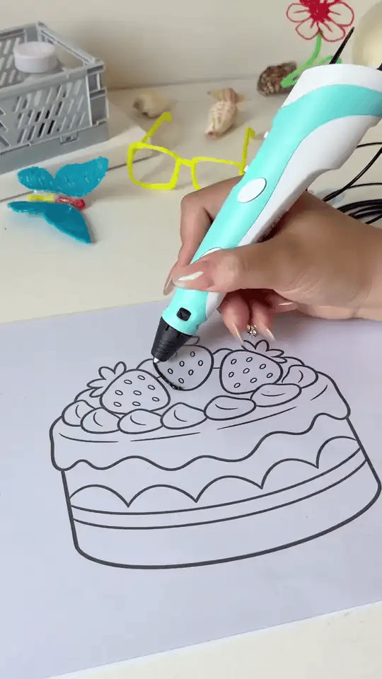 Caneta 3D preenchendo o desenho de um bolo com filamento colorido