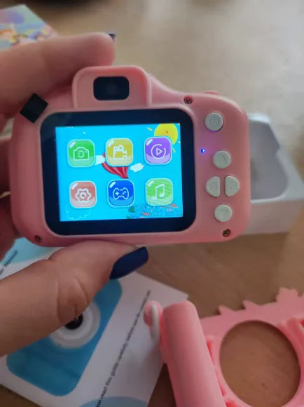Câmera rosa ligada mostrando o menu com ícones de foto, vídeo, galeria, ajustes, jogos e música