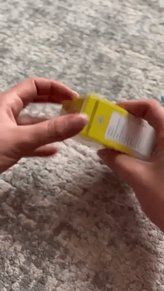 Mãos abrindo a caixa e espalhando os cards coloridos do FalaKids