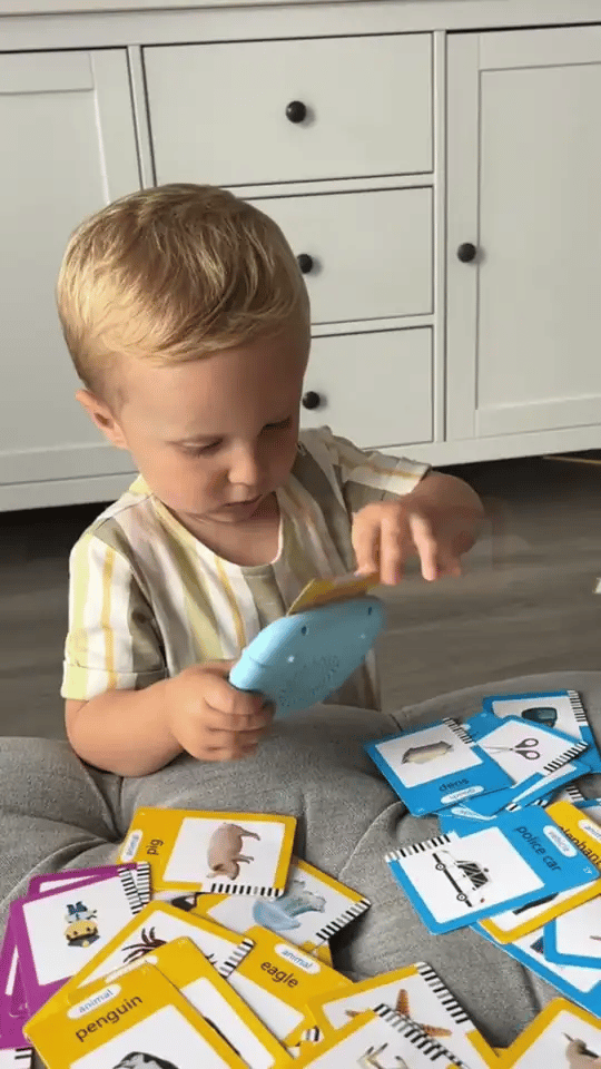 Criança brincando com o FalaKids e os cards espalhados